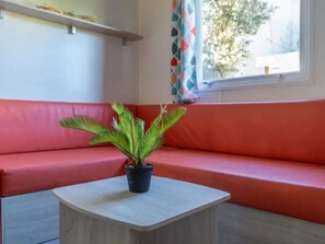 A room with a red sofa, a small table, and a potted plant. - Comfortable mobile home in Calvisson for 4 people (Calvisson)