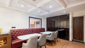 A dining area with a red upholstered booth, white tables, and grey chairs.