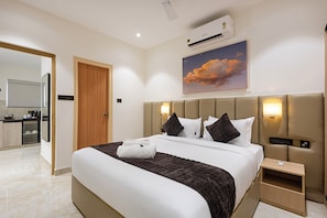 Une chambre d’hôtel avec un lit, une table de chevet et un tableau représentant un coucher de soleil.