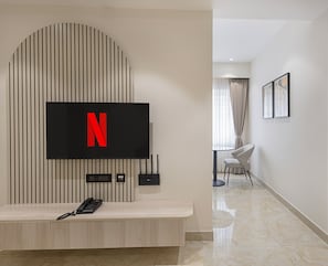 Un salon moderne avec un téléviseur fixé au mur, une console et un téléphone mural.