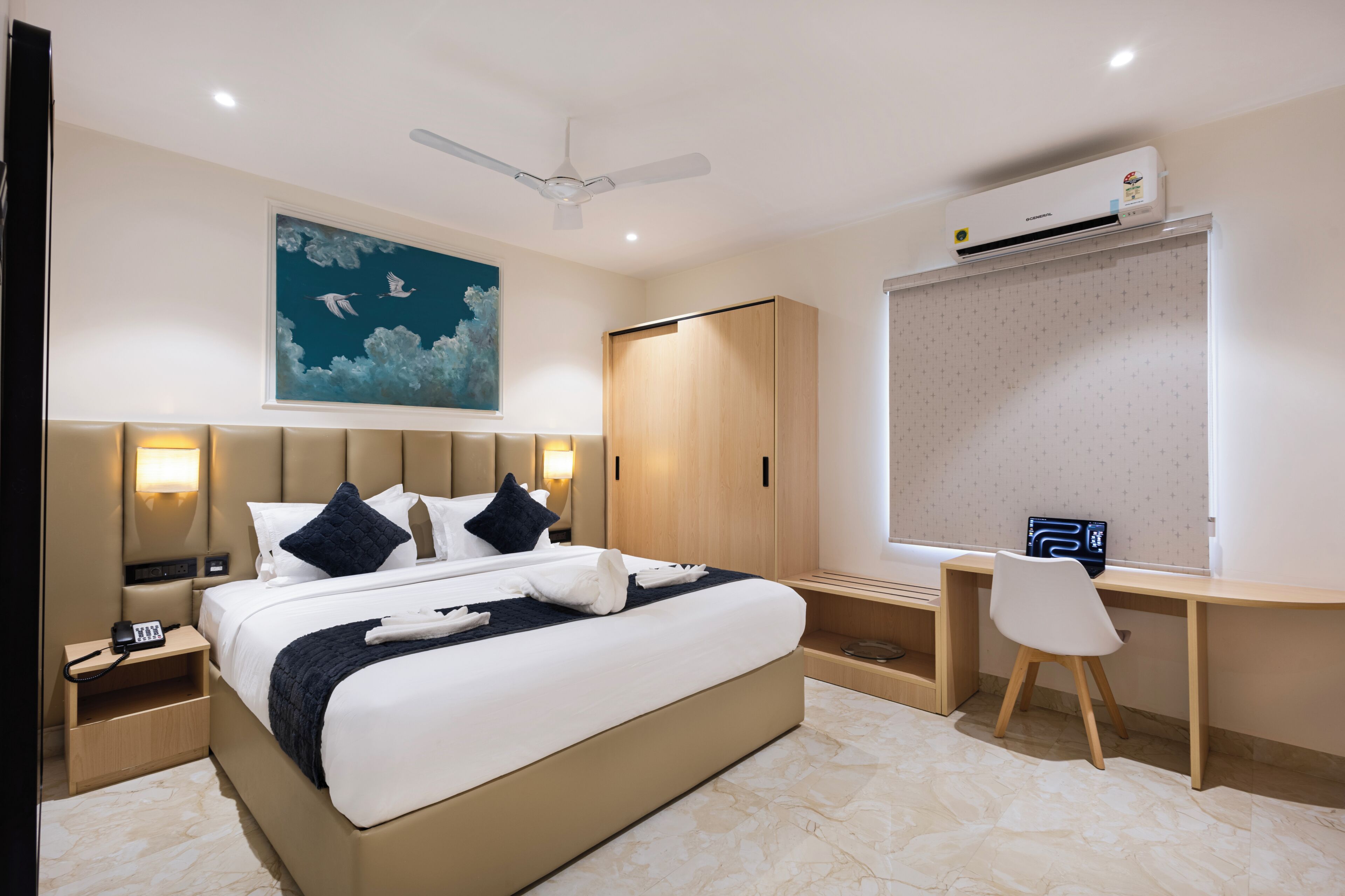 Une chambre d’hôtel équipée d’un lit, d’une table de chevet, d’un bureau, d’une chaise et d’un appareil de climatisation.