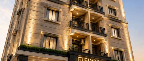 Un hotel de varios pisos con una entrada destacada, balcones y un cartel que indica que ofrece suites de lujo.