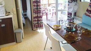 Una cocina compacta con comedor, un cubo de basura pequeño y un ventilador.