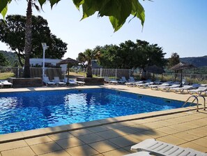 A swimming pool with sun loungers and umbrellas, surrounded by trees and a fence. - Cozy Chalet with Terrace - 1 bedroom, 2 people (Collias)