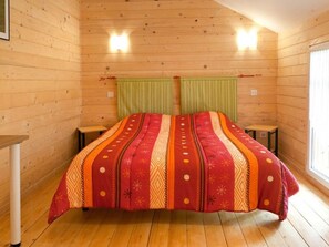 Une chambre dans une cabane en bois, avec un lit, deux tables de chevet et une fenêtre.