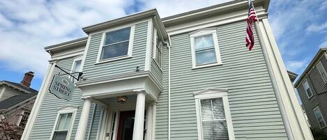 A two-story house with a red door, white trim, and a small front porch.