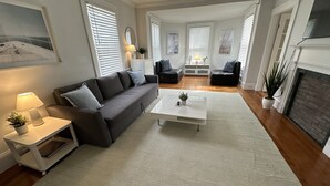 Ein modernes Wohnzimmer mit grauem Sofa, weißem Couchtisch und Kamin.