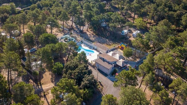 Eine Luftaufnahme eines Resorts mit Schwimmbad, umgeben von dichtem Wald.