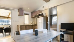 A compact kitchen with modern appliances, a dining area with a table and chairs, and a TV in the corner. - Cozy mobile home with terrace in Rivedoux-Plage for 4 ppl. (Rivedoux-Plage)