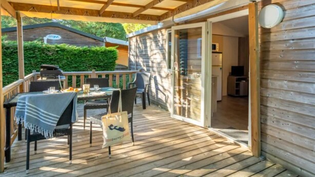 An outdoor deck with a covered seating area, a grill, and a view of the backyard. - Cozy mobile home with terrace in Rivedoux-Plage for 4 ppl. (Rivedoux-Plage)