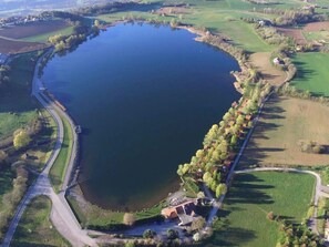 Une vue aérienne d’un lac entouré de champs et traversé par une route.