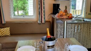 Een eethoek met een tafel voor twee personen, een champagnefles en een raam met gordijnen.