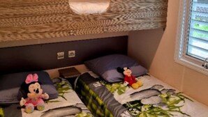 Een stapelbed met een gestreept hoofdeinde, twee kussens en twee knuffels op het onderste bed.