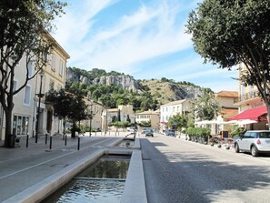 A street with buildings, a small water feature, and a mountain in the background. - Accessible Mobile Home with Terrace in Cavaillon (Cavaillon)