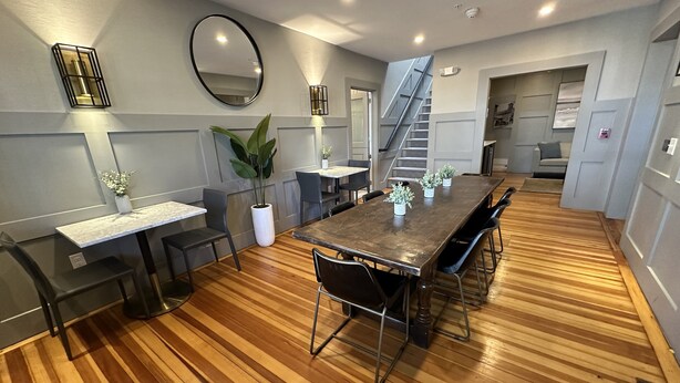 Un espace de repas moderne avec un plancher en bois, une table centrale entourée de chaises et un escalier menant à un niveau supérieur.