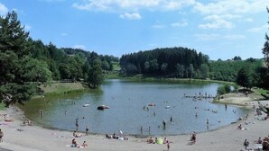 A lakeside setting with people swimming and relaxing on the shore. - Mobile-home 4 pers with bedrooms & garden furniture (Champagnac-le-Vieux)