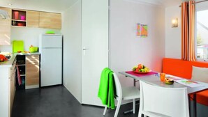 Una cocina compacta con refrigerador, una mesa de comedor con sillas y una pequeña sala de estar con sofá.