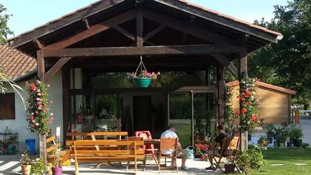Un espacio al aire libre cubierto con bancos y cestas de flores colgantes.