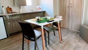 A compact kitchen with modern appliances, a dining table with chairs, and a wooden cabinet. - Cozy Mobile Home with Terrace for 2 in La Seyne-sur-Mer (La Seyne-sur-Mer)