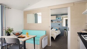 Een compacte kamer met een kitchenette, een eethoek met tafel en stoelen, een bank en een bed op de achtergrond.