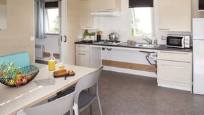 Een compacte keuken met een eethoek, inclusief een tafel met stoelen, een magnetron, een fornuis en kastjes.