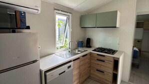 A compact kitchen with a dishwasher, a stove, and a window.