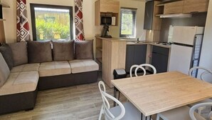 Un espace de vie compact comprenant un canapé, une table à manger et un coin cuisine.