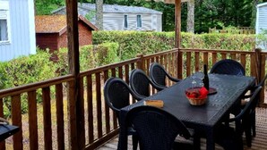 Eine überdachte Terrasse mit Tisch und Stühlen, umgeben von Holzbalkonen und Blick auf benachbarte Häuser.