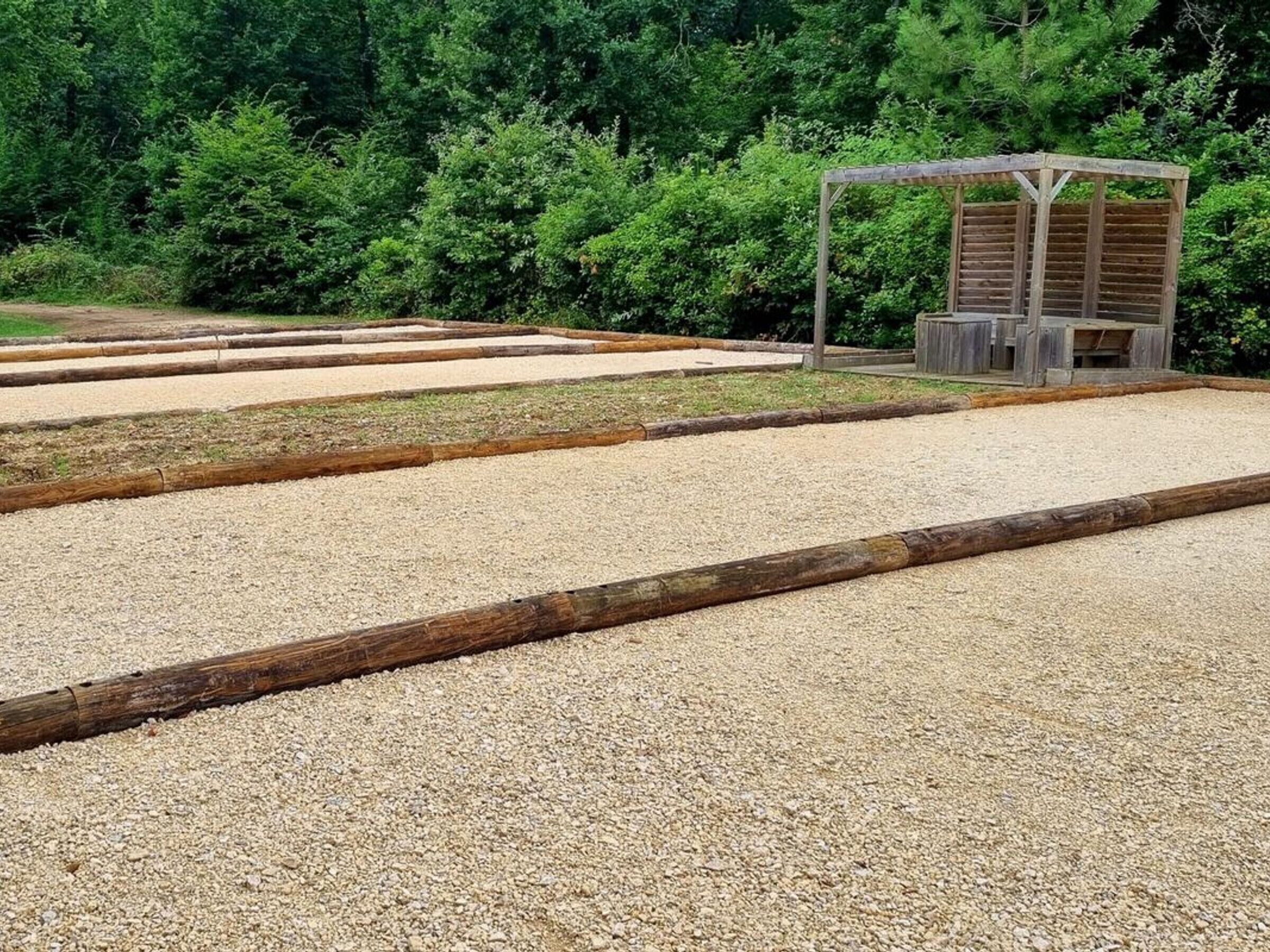 A gravel area with wooden borders and a wooden structure in the background.