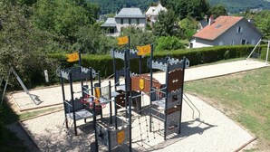 A playground with a castle-themed play structure, including a basketball hoop and climbing net. - Mobile Home 4 pers with Terrace in Vic-sur-Cère (Vic-sur-Cère)