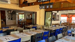 A restaurant with multiple tables and chairs, some with blue chairs and others with grey. - Mobile Home 4 pers with Terrace in Vic-sur-Cère (Vic-sur-Cère)