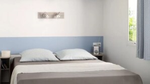 Una camera da letto con un letto, comodini, una lampada a parete e una finestra con tende.