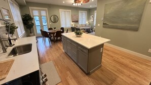 Una cocina moderna con una isla grande, piso de madera y un comedor con sillas y una mesa.