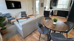 Una sala de estar moderna con un sofá gris, una mesa de centro y un comedor con una mesa y sillas de madera.