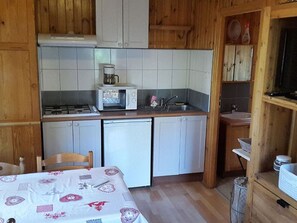 Eine kleine Küche mit weißen Schränken, einer Mikrowelle, einem Spülbecken und einem Geschirrspüler.