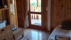Puinen huone, jossa on sänky, pieni työpöytä ja ikkuna, josta avautuu näkymä puiseen terassille.