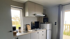 Eine kleine Küche mit weißen Schränken, einem Herd, einer Mikrowelle und einem Kühlschrank.