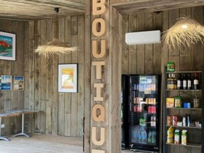 A wooden interior with a 'BOUTIQUE' sign, a refrigerator stocked with beverages, and a shelf with snacks. - Comfortable mobile home for 4 with terrace (Dolus-d'Oléron)