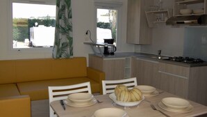 A compact kitchen with a dining area, a sofa, and a view of the outside. - Mobile home 3 bedrooms in Cavaillon with terrace (Cavaillon)
