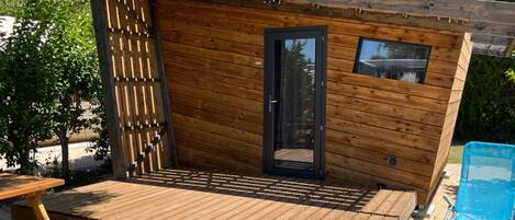Une cabane en bois dotée d’un balcon, d’une porte et d’une fenêtre.