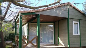 Un piccolo chalet a un piano con veranda, porta scorrevole in vetro e una finestra.