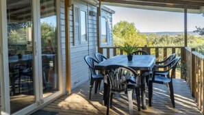 A covered outdoor patio with a table and chairs, a potted plant, and a view of the surrounding landscape. - Mobile Home 5 pers, Terrace at La Rouquette (Calvisson)