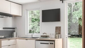 Una cocina compacta con lavavajillas, ventana y televisor de pantalla plana montado en la pared.