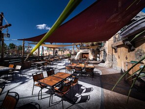 An outdoor patio with tables and chairs, a large umbrella, and a stone wall. - Comfortable mobile home with terrace for 6 people (Agde)