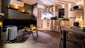 Eine moderne Küche mit einer zentralen Kochinsel, einem Essbereich mit Tisch und Stühlen sowie einem Wohnbereich mit Sofa und kleinem Tisch.