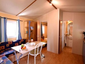 A compact room with a dining table, a bench, and a kitchenette area. - Spacious mobile home for 6 without special amenities (Vias)