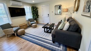 A living room with a grey sofa, a black coffee table, a wicker chair, and a large potted plant. - Downtown Newport Townhouse 2 Br/1.5 Bath/parking 2 Bedroom Apts (Newport)