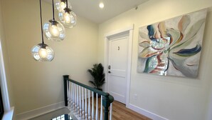 A hallway with a staircase, a door labeled "3", and a large abstract painting on the wall. - Downtown Newport Townhouse 2 Br/1.5 Bath/parking 2 Bedroom Apts (Newport)