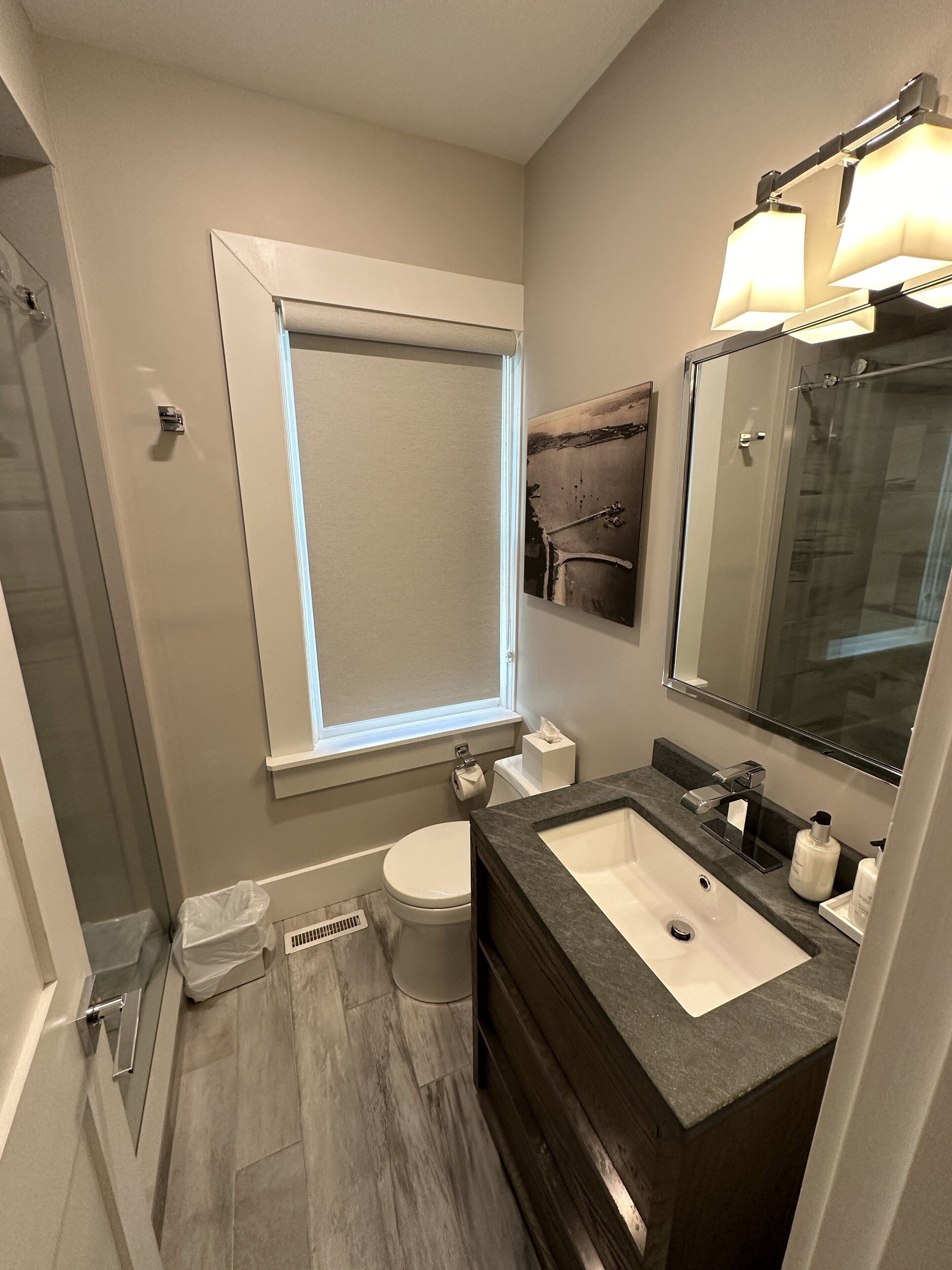 A modern bathroom with a glass shower enclosure, a toilet, and a vanity with a sink and mirror.