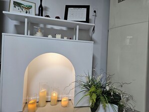A modern interior with a white fireplace, three lit candles, and a potted plant. - TOV STAY (Pyeongtaek)
